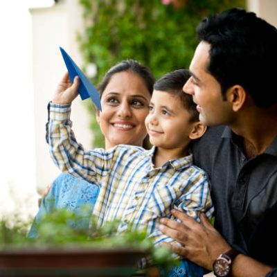 Happy parents with son throwing paper airplane in air